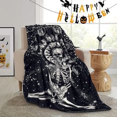 a halloween themed blanket with a skeleton on it and pumpkins hanging in the background