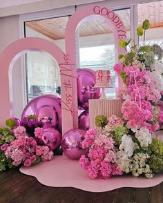 pink and white flowers are on display in front of a large sign that says goodbye