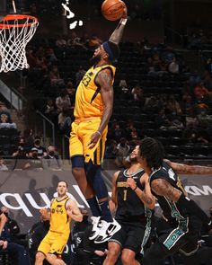 a basketball player dunking the ball in front of other players and fans at a game