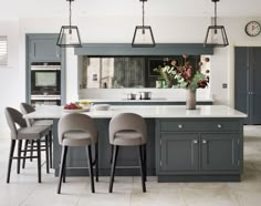 a large kitchen with gray cabinets and stools