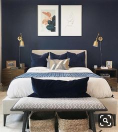 a bedroom with blue walls, white bedding and two framed pictures on the wall