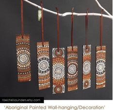 an assortment of hand painted hanging decorations on a tree branch in front of a dark background