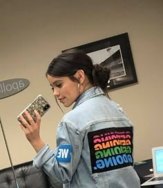 a woman in denim jacket holding up a cell phone