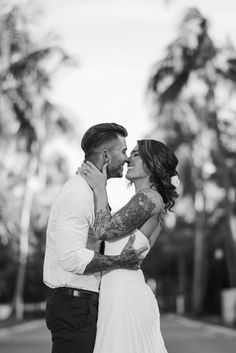 a bride and groom kissing in front of palm trees