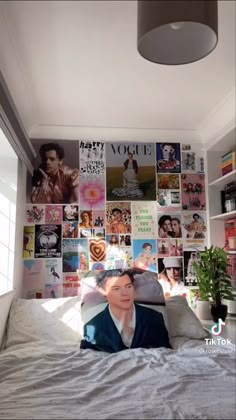 a woman laying on top of a bed covered in pictures and posters above her head