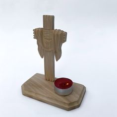 a wooden statue with a red candle in front of it on a white background,