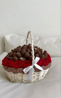 a basket filled with chocolates and roses on top of a bed