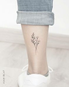 a woman's foot with a small flower tattoo on the left side of her leg