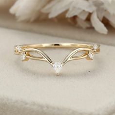 a gold ring with white stones on it and a flower in the back ground next to it