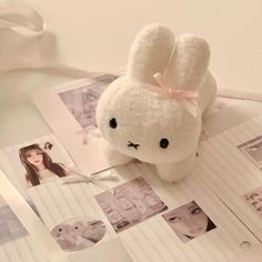 a white stuffed animal sitting on top of a table next to pictures and a ribbon