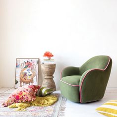 a green chair sitting on top of a white floor next to a vase filled with flowers