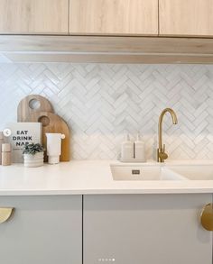 a kitchen with white counter tops and gold faucets on the wall above the sink