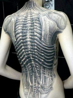 the back of a woman's body is covered in tattoos and skeleton parts,