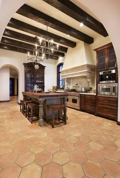 a large kitchen with an island in the center and wooden cabinets on both sides, surrounded by stone flooring