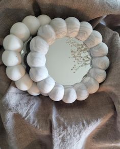 a mirror that is sitting on top of a cloth covered tablecloth with shells around it