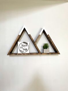 two wooden triangle shelves with a plant on top