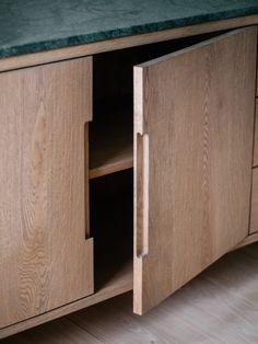 a close up of a wooden cabinet with green counter top and drawers on the bottom