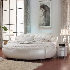 a white round bed sitting in a bedroom on top of a hard wood floor next to a window