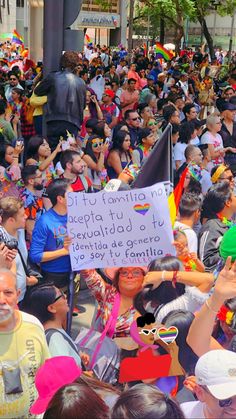 a large group of people standing around each other in the street with signs and balloons