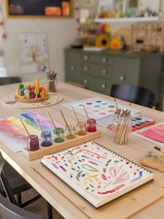 the table is set up with art supplies and watercolors for kids to paint