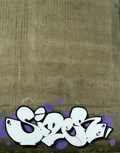 graffiti is painted on the side of a concrete wall with purple and white spray paint