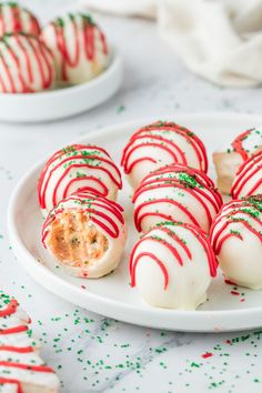 white and red desserts with green sprinkles on a plate next to other food items