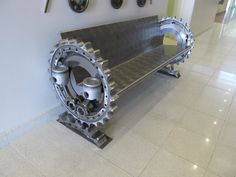 a metal bench sitting on top of a tile floor next to wall with clocks above it