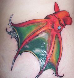 an octopus tattoo on the side of a woman's stomach with red, green and orange colors