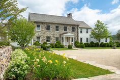 a large stone house sitting on top of a lush green field