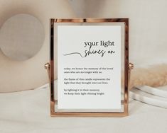 a sign that says your light shines on in front of a white background with a gold frame