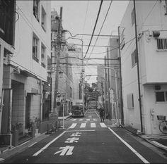 an empty street with buildings on both sides and people walking down the road in between