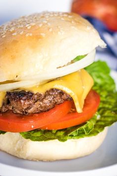 a cheeseburger with tomatoes, onions and lettuce is on a plate