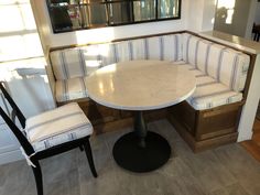 a corner table with two chairs and a bench next to it in a living room