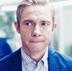 a man in a blue jacket and plaid shirt is looking at the camera with an intense look on his face