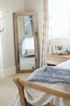 a bedroom with a bed, dresser and large mirror in front of the window on the wall