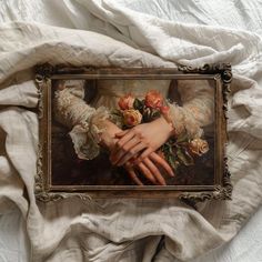 there is a painting on the wall with hands holding flowers in it's frame