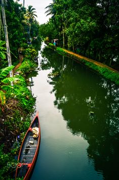 there is a boat on the water in the middle of the river and trees around it