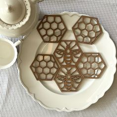 a white plate topped with cut out honeycombs next to a tea pot and saucer