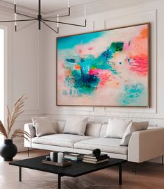 a living room filled with furniture and a large painting hanging on the wall above it