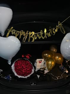 a birthday party with balloons, flowers and gifts in the trunk of a car at night