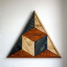 a wooden wall hanging on the side of a white wall next to a brown and black triangle