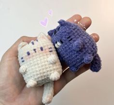 two small crocheted stuffed animals are held in someone's hand, one is blue and the other is white