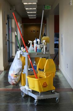 a cleaning cart with two mop's and buckets on it in a hallway