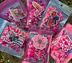 some pink bags filled with lots of different types of beads and stickers on top of each bag