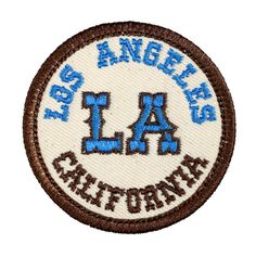 an embroidered patch with the word los angeles in blue and brown on it, that says la california