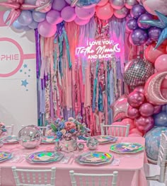 a table set up for a party with balloons and streamers