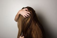 a woman holding her hair in front of her face with one hand on the back of her head