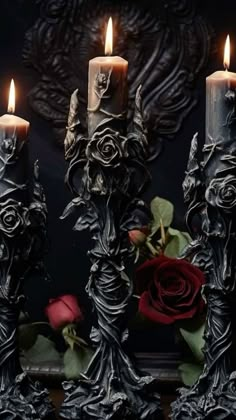 three candles with roses in front of them