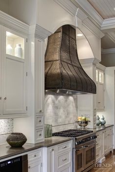 a kitchen with white cabinets and an oven hood over the stove in front of it