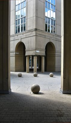 some balls are sitting in the middle of an empty courtyard with arches and windows on either side